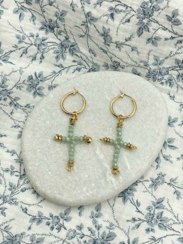 de jolies créoles en acier inoxydable dorée avec une ,pendentif en croix constitué de perles en verres vert d'eau et de perles dorées