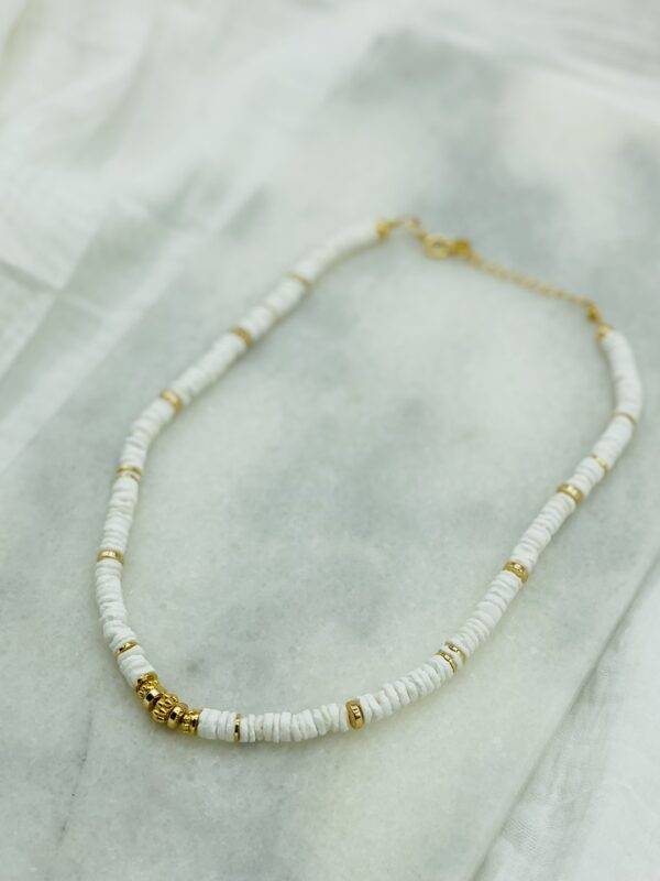 Un collier surfeur ajustable composé de perles naturelles de coquillage et de perles dorées à l'or fin. fermoir ajustable