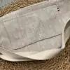 Le dos du sac banane en Lin naturel aux couleurs intemporelles avec sa grande poche plaquée permettant d'y glisser un téléphone portable