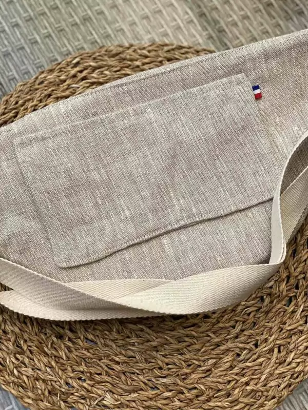 Le dos du sac banane en Lin naturel aux couleurs intemporelles avec sa grande poche plaquée permettant d'y glisser un téléphone portable