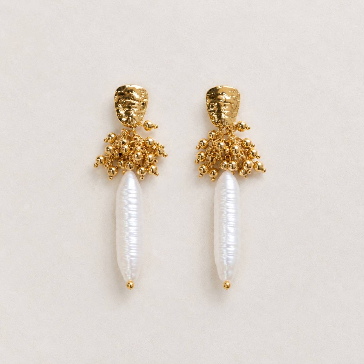 Boucles d'oreilles pendantes avec une perle d'eau douce allongée réhaussée d'acier inoxydable doré