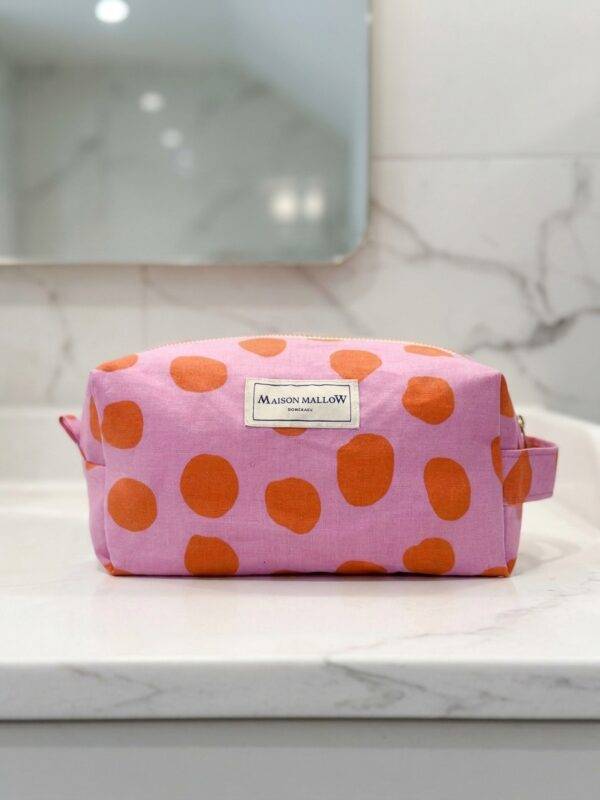 Trousse de toilette à pois rose face sur meuble en marbre