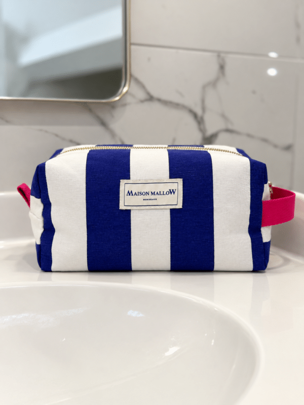Trousse rayée bleu et blanc avec poignée rose sur lavabo