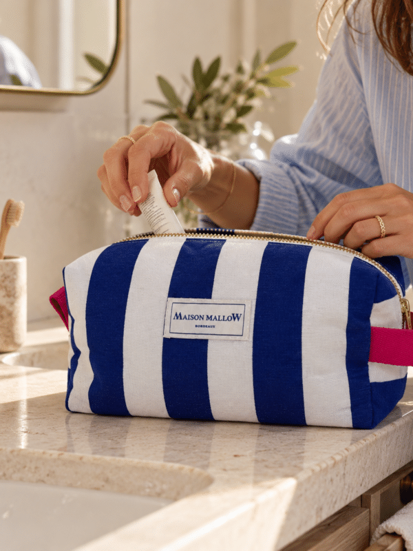 Trousse rayée bleu et blanc avec poignée rose sur comptoir en marbre